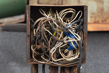 wires interconnected in a rusty old crowded box for wires. electrical safety violation