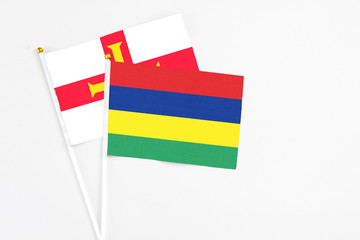 Mauritius and Guernsey stick flags on white background. High quality fabric, miniature national flag. Peaceful global concept.White floor for copy space.