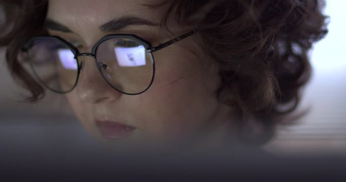 Hacker Woman Tries to Get Confidential Information. Pretty hacker woman attacks confidational data using programme code. We see the reflection of the code in her glasses