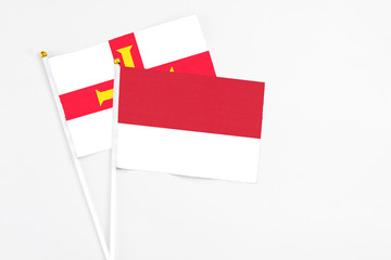 Monaco and Guernsey stick flags on white background. High quality fabric, miniature national flag. Peaceful global concept.White floor for copy space.
