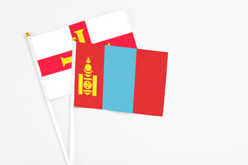Mongolia and Guernsey stick flags on white background. High quality fabric, miniature national flag. Peaceful global concept.White floor for copy space.