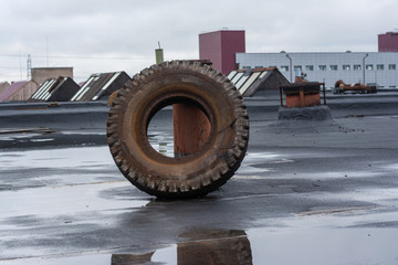 factory roof. there is a big old dirty tire from the wheel, leaning on the air pipe.
