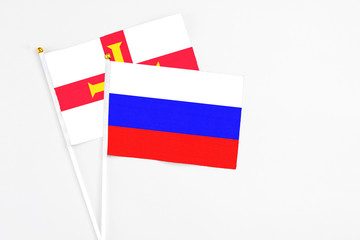 Russia and Guernsey stick flags on white background. High quality fabric, miniature national flag. Peaceful global concept.White floor for copy space.
