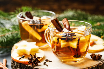 Hot drink for New Year, Christmas or autumn holidays. Mulled cider or spiced tea or mulled white wine with lemon, apples, cinnamon, anise, cloves. - 302749401
