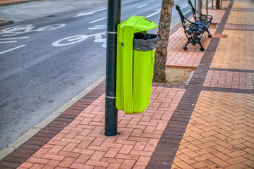Green trash bin on sidewalk