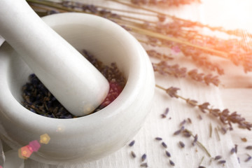 making organic cosmetics with dried lavender In marble mortar and pestle on white wooden background top view. tonned image - obrazy, fototapety, plakaty