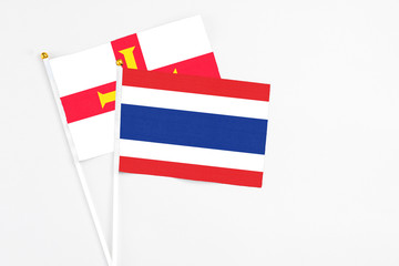 Thailand and Guernsey stick flags on white background. High quality fabric, miniature national flag. Peaceful global concept.White floor for copy space.