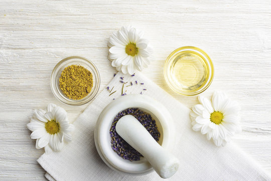 Composition With Dried Lavender Flowers In White Marble Pestle And Mortar And Natural Chamomile Oil Cosmetic In Glass Jar On White Background, Top View With Free Copy Space