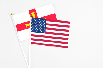 United States and Guernsey stick flags on white background. High quality fabric, miniature national flag. Peaceful global concept.White floor for copy space.