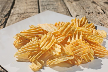 Background corrugated golden chips with texture. Potato chips is snack, ready to eat and fat food or junk food. Horizontal. Top view.