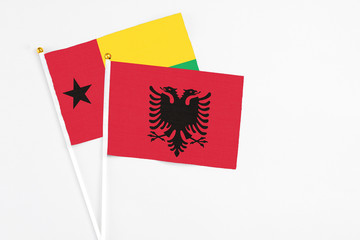 Albania and Guinea Bissau stick flags on white background. High quality fabric, miniature national flag. Peaceful global concept.White floor for copy space.