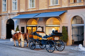 Horse fiaker on street with snow in Salzburg of Austria. Mozart city in Europe at winter. Carriage fiacre transport. Panoramic view and cityscape of beautiful old Austrian town of Salzburgerland.