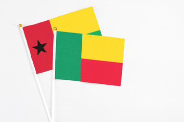 Benin and Guinea Bissau stick flags on white background. High quality fabric, miniature national flag. Peaceful global concept.White floor for copy space.