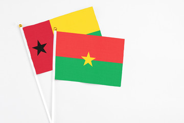 Burkina Faso and Guinea Bissau stick flags on white background. High quality fabric, miniature national flag. Peaceful global concept.White floor for copy space.