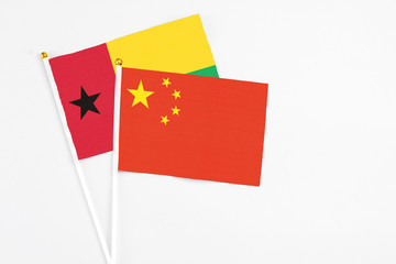 China and Guinea Bissau stick flags on white background. High quality fabric, miniature national flag. Peaceful global concept.White floor for copy space.
