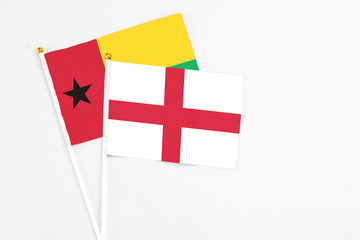 England and Guinea Bissau stick flags on white background. High quality fabric, miniature national flag. Peaceful global concept.White floor for copy space.