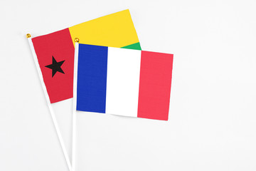France and Guinea Bissau stick flags on white background. High quality fabric, miniature national flag. Peaceful global concept.White floor for copy space.