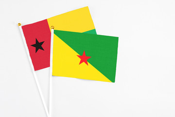 French Guiana and Guinea Bissau stick flags on white background. High quality fabric, miniature national flag. Peaceful global concept.White floor for copy space.