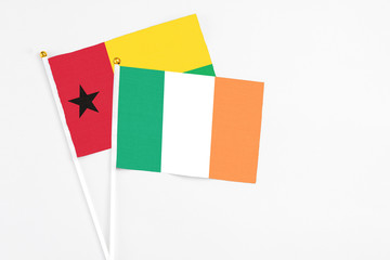 Ireland and Guinea Bissau stick flags on white background. High quality fabric, miniature national flag. Peaceful global concept.White floor for copy space.