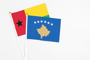 Kosovo and Guinea Bissau stick flags on white background. High quality fabric, miniature national flag. Peaceful global concept.White floor for copy space.