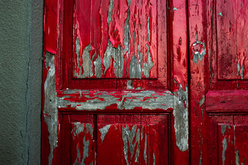Red paint peeling off an old wooden door.