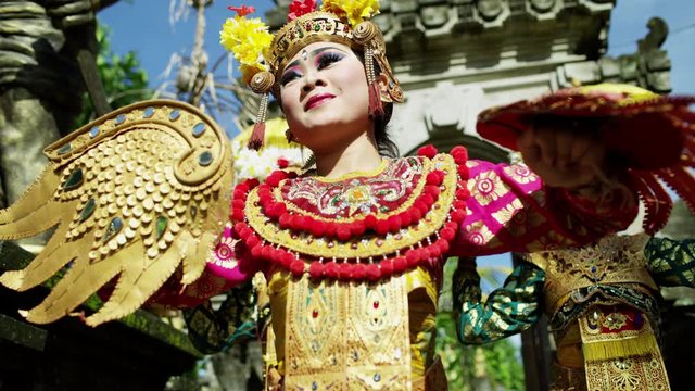 Young Balinese dancing girls performing near religious temple 