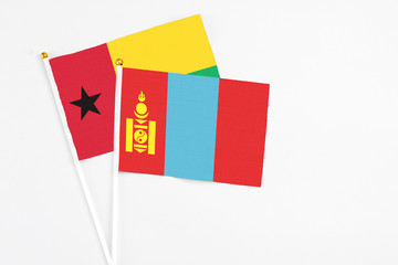 Mongolia and Guinea Bissau stick flags on white background. High quality fabric, miniature national flag. Peaceful global concept.White floor for copy space.