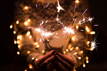 Girl in a sweater with a deer holds burning sparklers. Christmas Eve concept. Happy new year...