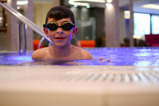 Cute happy little boy swimming and snorking in the swimming pool indoor. Young boy kid child eight years old splashing in swimming pool having fun leisure activity
