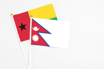 Nepal and Guinea Bissau stick flags on white background. High quality fabric, miniature national flag. Peaceful global concept.White floor for copy space.