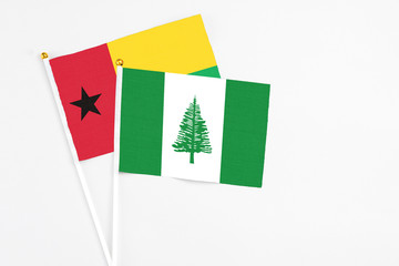 Norfolk Island and Guinea Bissau stick flags on white background. High quality fabric, miniature national flag. Peaceful global concept.White floor for copy space.