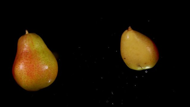 Two juicy tasty pears collide with each other on a black background