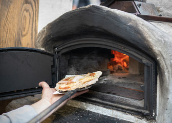 Chef taking out pizza from an oven