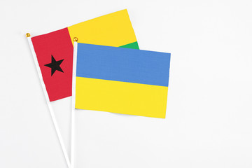 Ukraine and Guinea Bissau stick flags on white background. High quality fabric, miniature national flag. Peaceful global concept.White floor for copy space.
