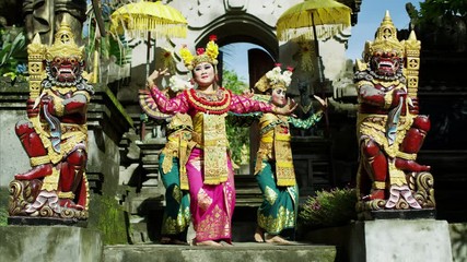 Young Balinese dancing girls performing near religious temple 