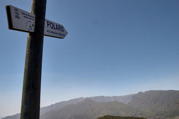 Señal que marca la distancia a la estrella polar desde lo alto de las montañas, con un cielo azul y la cordillera al fondo