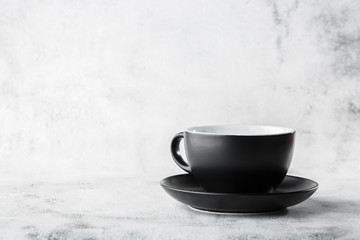 Black cup isolated on a white marble background. Horizontal photo. Tableware shop. Dishes shop....