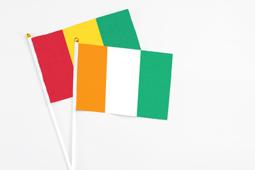 Cote D'Ivoire and Guinea stick flags on white background. High quality fabric, miniature national flag. Peaceful global concept.White floor for copy space.