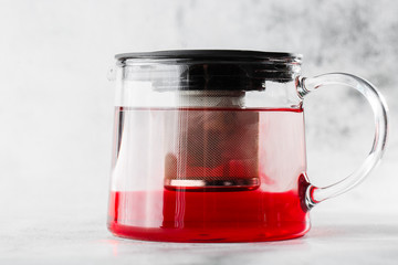 Glass teapot of red, fruit or berries tea isolated on bright marble background. Overhead view, copy space. Advertising for cafe menu. Coffee shop menu. Horizontal photo.