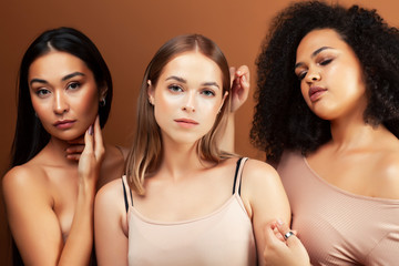 young pretty asian, caucasian, afro woman posing cheerful together on brown background, lifestyle diverse nationality people concept