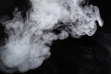 Puffs of white, gray smoke spread on a black background, curling in a fancy dance.