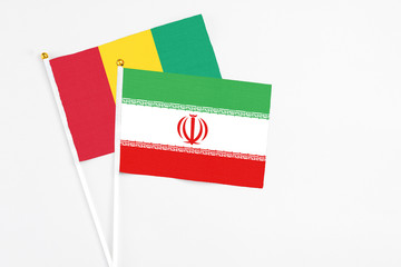 Iran and Guinea stick flags on white background. High quality fabric, miniature national flag. Peaceful global concept.White floor for copy space.