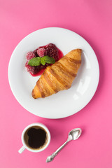 Continental breakfast with croissant, coffee  and raspberry jam on the pink background. Top view. Copy space. Location vertical.