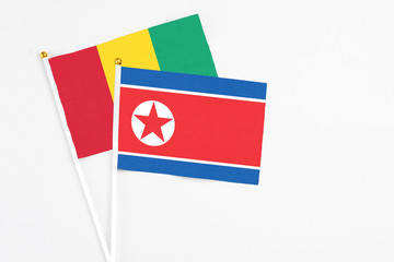North Korea and Guinea stick flags on white background. High quality fabric, miniature national flag. Peaceful global concept.White floor for copy space.