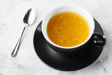 Sea buckthorn tea in dark cup isolated on bright marble background. Overhead view, copy space. Advertising for cafe menu. Coffee shop menu. Horizontal photo.