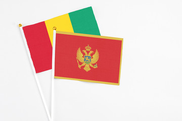 Montenegro and Guinea stick flags on white background. High quality fabric, miniature national flag. Peaceful global concept.White floor for copy space.