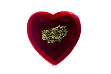 Dried cannabis buds CBD in heart shape plate.