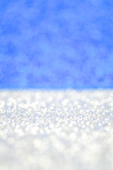 White sparkle snow flakes on blue sky background. Shimmer glitter defocused bokeh wallpaper