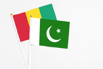 Pakistan and Guinea stick flags on white background. High quality fabric, miniature national flag. Peaceful global concept.White floor for copy space.
