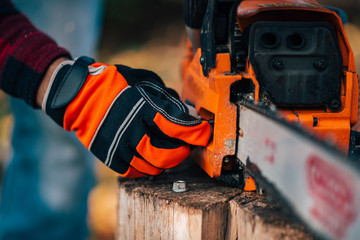 Close-up image of a man starting chainsaw.